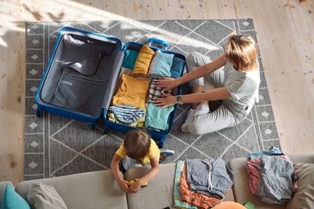 parent packing clothes while child plays